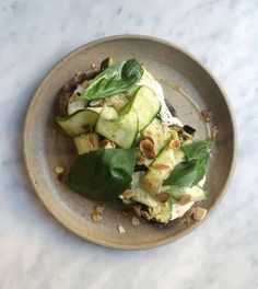 a plate topped with cucumbers and spinach on top of a marble table