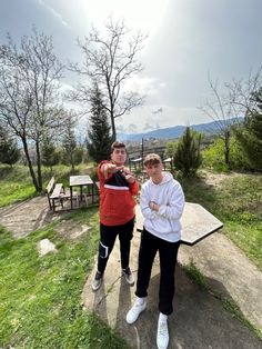 two people posing for a photo in front of a picnic table with mountains in the background