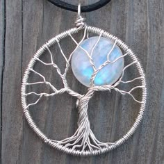 a tree of life pendant with a blue stone in the center on a black cord necklace