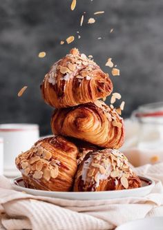 a pile of croissants sitting on top of a white plate covered in nuts