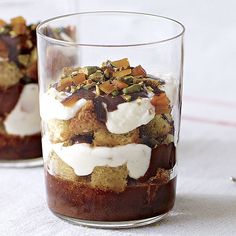 two glasses filled with dessert sitting on top of a table