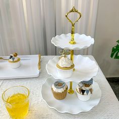 three tiered trays with cupcakes and pastries on them sitting on a table