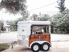 the food truck is parked on the side of the road in front of some trees