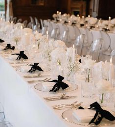 the table is set with white flowers and black ribbon napkins for an elegant wedding reception