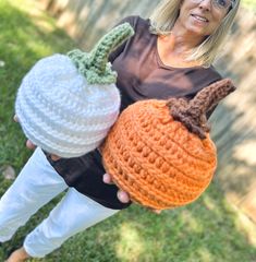 a woman holding three crocheted pumpkins in her hands