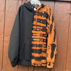 an orange and black hoodie hangs on a wooden wall