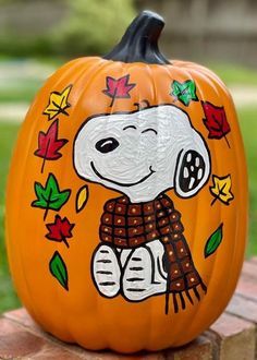 a painted pumpkin with a dog on it sitting on top of a brick wall in the grass