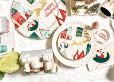 a table topped with plates covered in christmas themed food and decorations, including candy bars