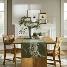 a dining room table with two chairs and a vase filled with plants on top of it