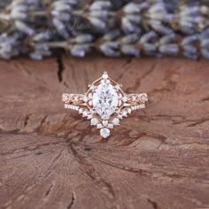 a close up of a ring on top of a tree stump with lavender flowers in the background