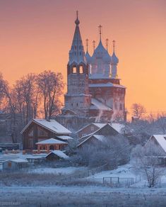 an old church in the middle of winter with snow on the ground and trees around it