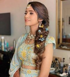 a woman with long hair wearing a blue dress and gold jewelry is standing in front of a mirror