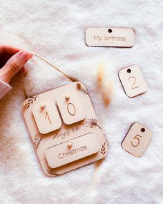 a person is holding some wooden tags with numbers on them and the tag says merry christmas