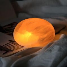 an orange lamp sitting on top of a bed next to a fork and napkins