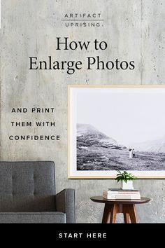 a chair sitting next to a table in front of a wall with an image on it