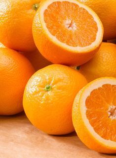 a pile of oranges sitting on top of a wooden table next to each other