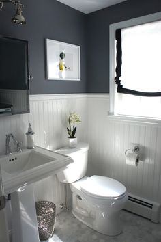 a white toilet sitting next to a sink in a bathroom under a window with blinds