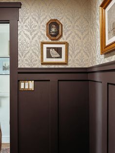 a woman is standing in the doorway of a room with wallpaper and pictures on the walls