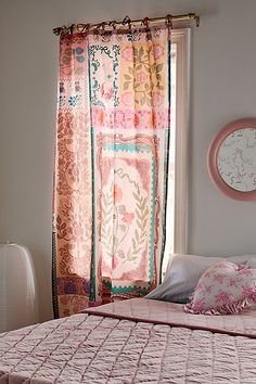 a bed with pink and green bedspread next to a window