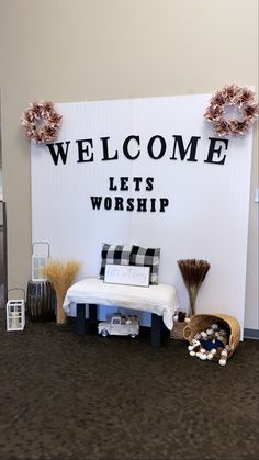 a sign that says welcome lets worship on the side of a room with furniture and decorations