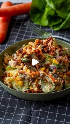 a bowl filled with food next to carrots and lettuce on a table