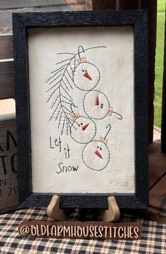 an embroidered snowman is displayed in a frame