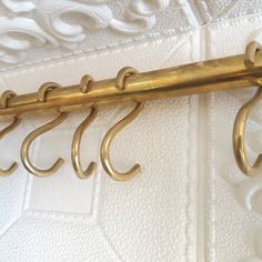 a close up of a gold coat rack on a white wall with ornate designs and scrolls