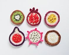 four crocheted ornaments are arranged on a white surface