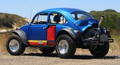 an old blue car parked on top of a dirt road