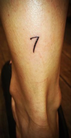 a woman's lower leg with a small tattoo on her left thigh and the number seven