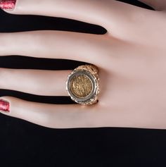 a woman's hand wearing a ring with a coin on it