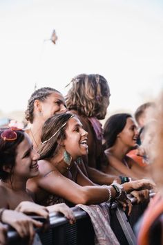 a group of people standing next to each other at a music festival with their hands in the air