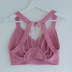 a pink crocheted bralet hanging on a white hanger