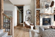 a living room filled with furniture and a fire place next to a stair case in front of a stone fireplace