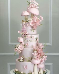 a three tiered cake decorated with pink flowers and mushrooms