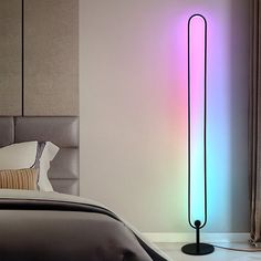 a bedroom with a bed and a colorful light on the wall next to it's headboard