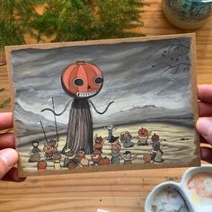 a person holding up a painting with an image of a pumpkin on it's face