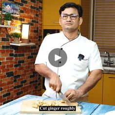 a man cutting up food on top of a wooden table in front of a brick wall