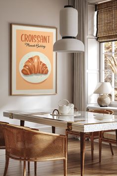 a dining room table with chairs and a poster on the wall above it that says croissant