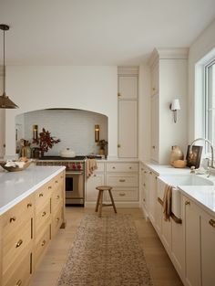 a kitchen with white cabinets and an area rug in front of the counter top that matches the floor