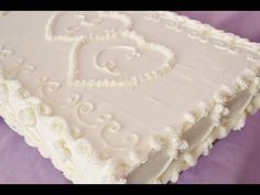 a large white cake sitting on top of a purple table cloth covered in frosting