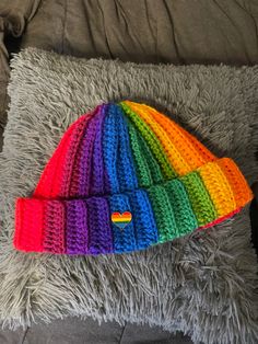 a multicolored knitted hat laying on top of a gray pillow in a room