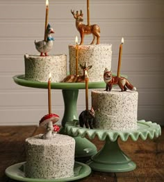 there are many small cakes with candles on the cake platter and one is decorated with deer figurines