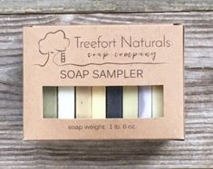 the soap sample is packaged in a cardboard box on a wooden surface, and it contains five different types of soaps