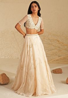 Featuring a beautiful cream lehenga made from shimmering metallic organza fabric, creating an ethereal glow. This elegant set comes with a matching blouse featuring delicate aari hand embroidery, adding a touch of intricate detail. A flowing silk organza dupatta completes the look, draped softly to highlight the outfit's timeless grace. Ideal for a reception at a destination wedding, this ensemble captures the heart with its simple beauty and elegance. Composition : Lehenga, Blouse, Dupatta - Organza Care: Dry Clean Only and Vacuum Storage This product can be customized for sleeves, length of blouse and neckline Delivery : 4-6 weeks as the product is hand crafted. Check Size Guide or choose MySize for free customisation (All Sizes above XL can be made at 15% additional cost) For more infor Light Weight Lehenga, Cream Lehenga, Front Blouse Designs Latest For Lehenga, Lehenga Designs In Organza, Lehenga Sleeves Design, Champagne Indian Outfit, Organza Lehenga Blouse Designs, Reception Lehanga, Gold Organza Lehenga For Formal Occasions