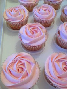 cupcakes with pink frosting sitting on a white tray in the shape of a rose