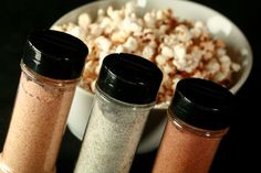 three salt and pepper shakers next to a bowl of popcorn