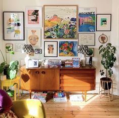 a living room filled with furniture and pictures on the wall next to a wooden dresser