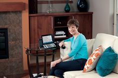 a woman sitting on a couch in front of a fire place with a remote control