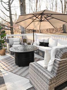 an outdoor living area with wicker furniture and an umbrella over the fire pit table